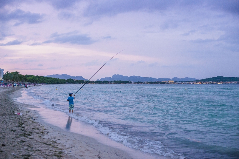 Person angelt an einem flachen Strandabschnitt