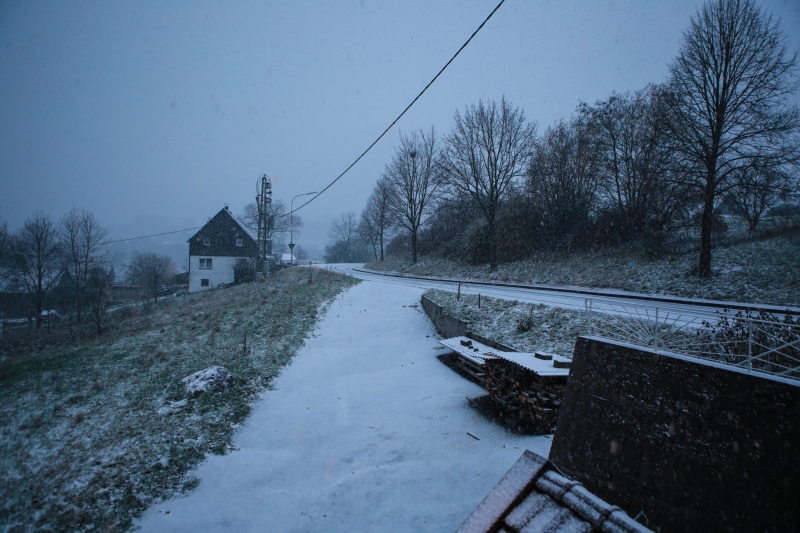 Verschneiter Weg durch eine winterliche Hügellandschaft