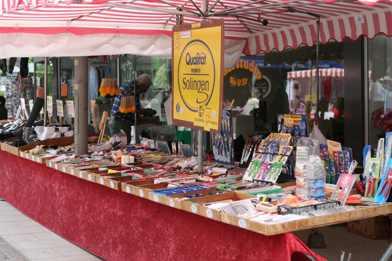 Marktstand mit handgefertigten Waren unter einer rot-weißen Markise