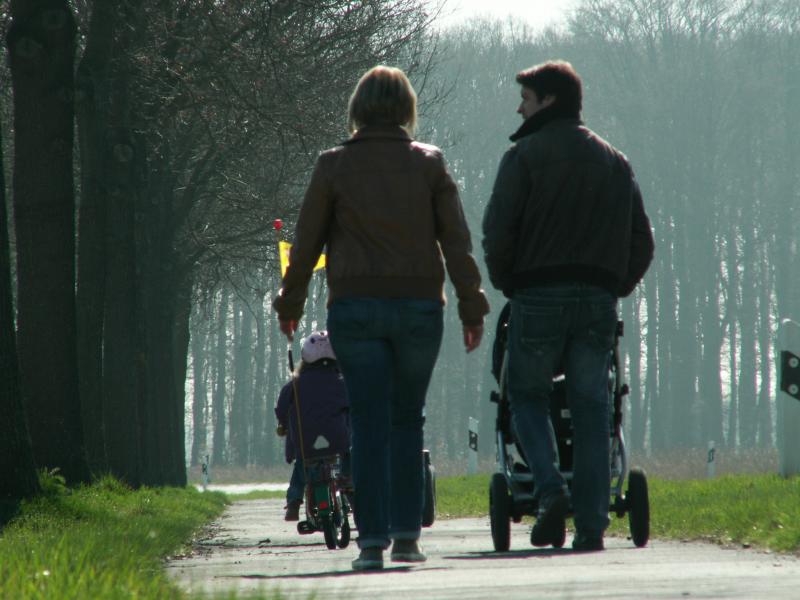 Familie mit Kinderwagen und Kind auf einem Waldweg