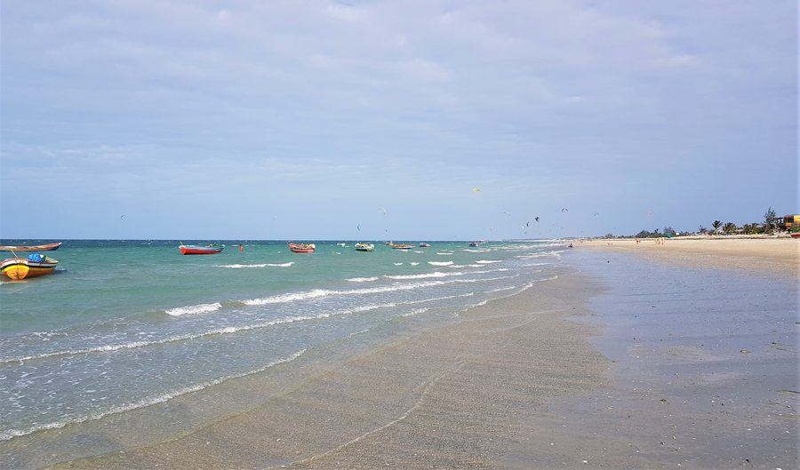 Sandstrand der Praia do Preá in Cruz im brasilianischen Bundesstaat Ceará mit Booten und Kites im Hintergrund