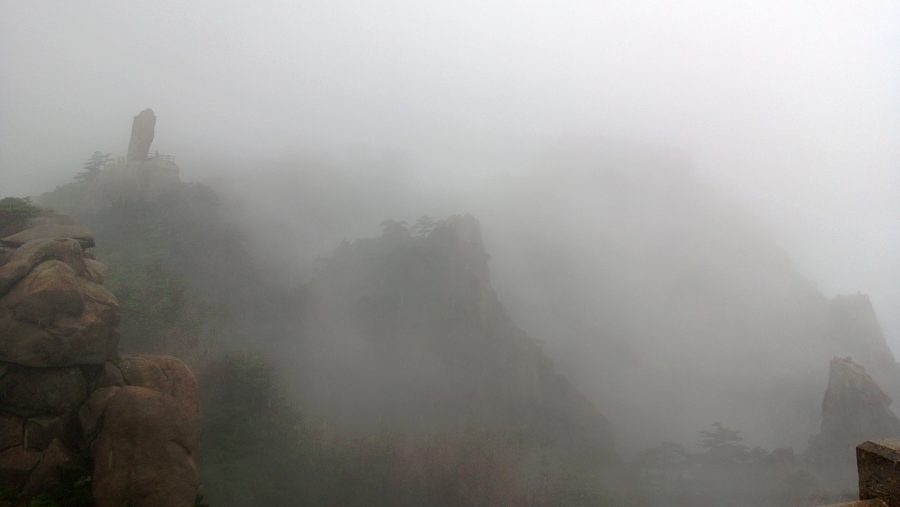 Berglandschaft des Huangshan in Anhui mit markanten Felsformationen, Kiefern und Nebel