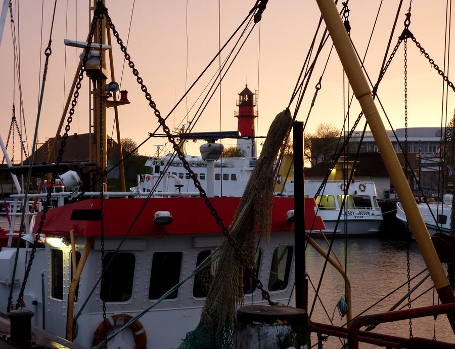 Hafen von Büsum mit Booten und Leuchtturm bei Sonnenuntergang