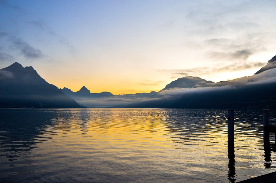 Sonnenaufgang über dem Vierwaldstättersee bei Beckenried mit Bergen im Hintergrund.