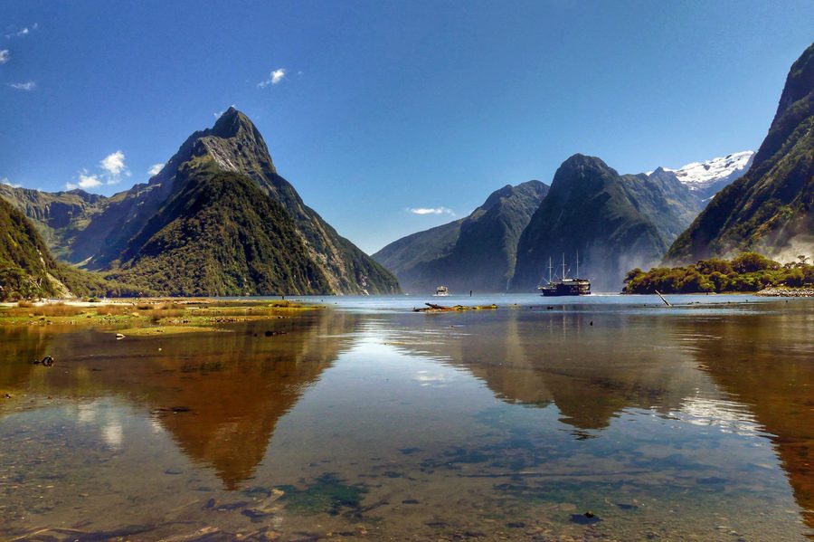 Milford Sound in Neuseeland mit steilen, von Gletschern geformten Felswänden, Wasserfällen und dunklem Fjordwasser