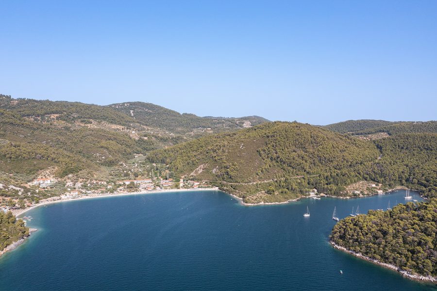 Luftaufnahme des Strands Panormos auf Skopelos mit türkisblauem Wasser und bewaldeter Küste