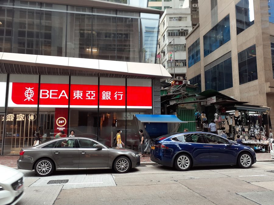 Straßenszene an der Queen's Road Central in Hongkong mit einer Filiale der Bank of East Asia.