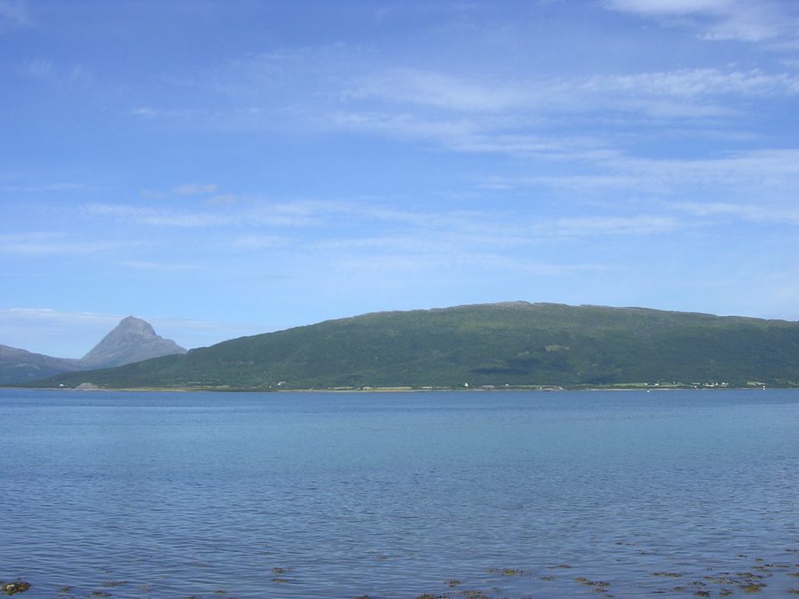 Handnesøya in der Gemeinde Nesna, von Nesna aus gesehen, mit dem Berg Tomskjeveln auf der Insel Tomma im Hintergrund.