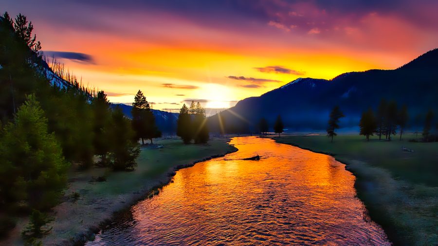 Sonnenuntergang über dem Yellowstone-Nationalpark mit warmem Licht und Wolken über der Landschaft.