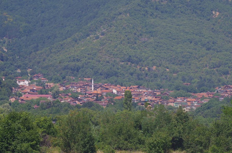 Panoramablick auf das Dorf Podgorci mit bewaldeter Berglandschaft