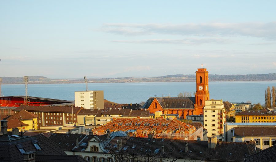 Teil von Neuchâtel mit der Kirche Notre-Dame-de-l’Assomption und dem Neuenburgersee im Abendlicht