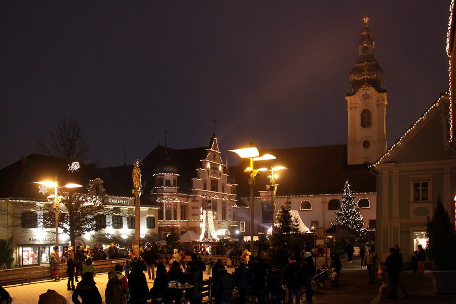Beleuchteter Hauptplatz von Hartberg mit historischen Gebäuden, Mariensäule, Rathaus und Pfarrkirche Sankt Martin