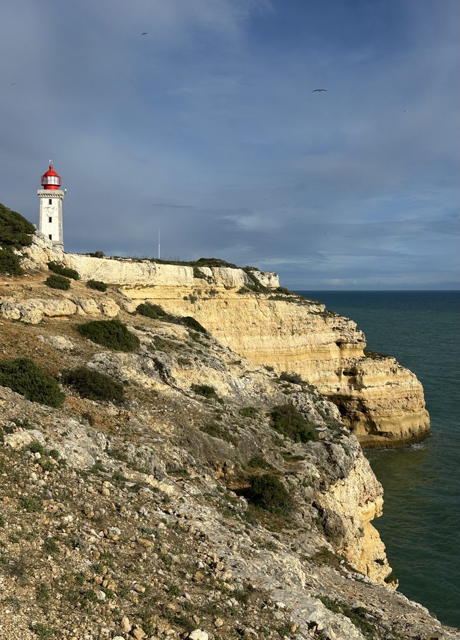 Farol de Alfanzina lighthouse on rugged coastal cliffs overlooking the ocean near Carvoeiro, Faro, Portugal