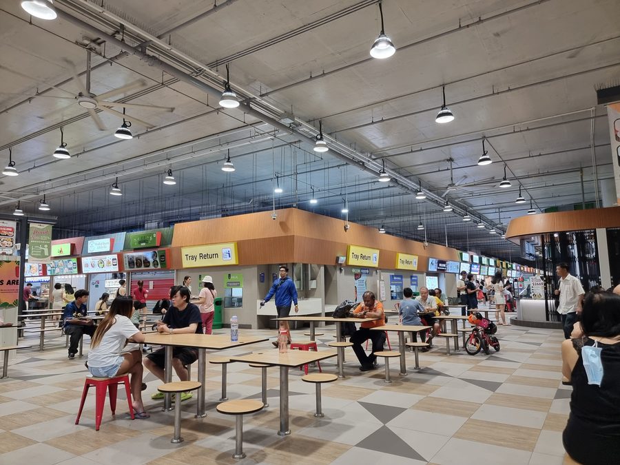 Innenraum des Woodleigh Village Hawker Centre mit verschiedenen Essensständen