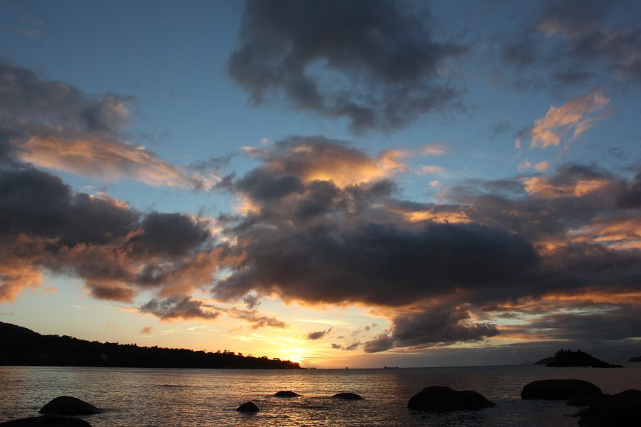 Praia Julião em Ilhabela, São Paulo, ao pôr do sol, com a costa e a vegetação da ilha