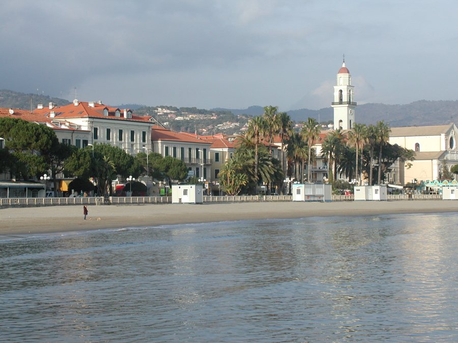 Strand an der Italienischen Riviera mit Palmen und Gebäuden am Ufer