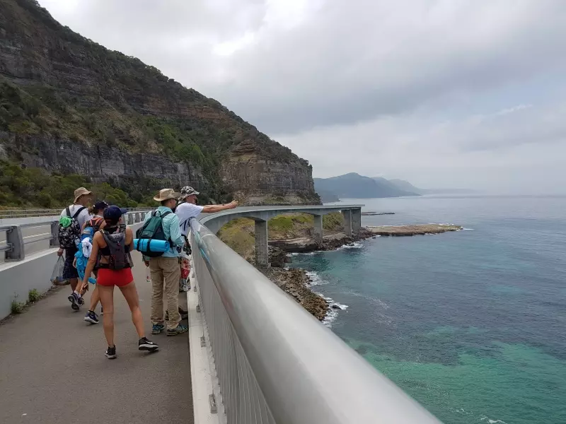 Reisende auf einer Brücke an der Küste